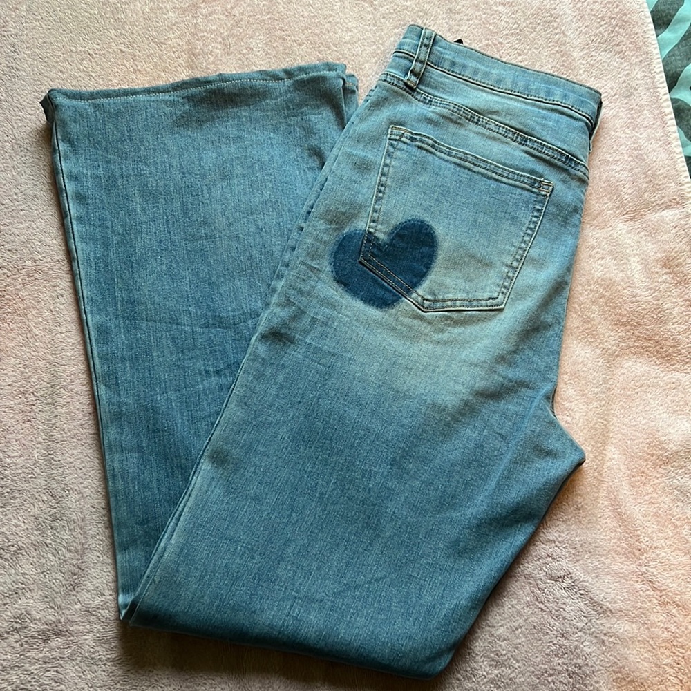 Light blue jeans, bootcut style with a heart on the left cheek.